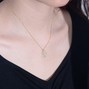 Close-up of golden S925 sterling silver Om symbol pendant necklace on female collarbone