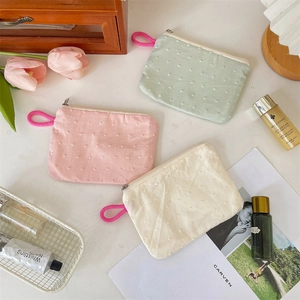 Macro detail of textured macaron lipstick pouches with 3D dotted embroidery and zipper