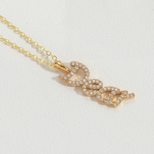 Detailed view of a gold Deed pendant necklace with sparkling pavé crystals on white leather
