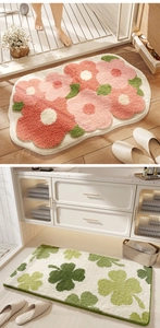 Detail of plush absorbent bath mats featuring floral and clover patterns in bathroom setting