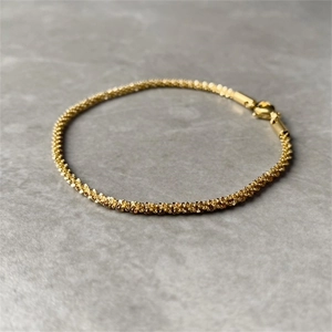 Detail eines funkelnden goldfarbenen Blumenketten-Armbands mit sicherem Karabinerverschluss