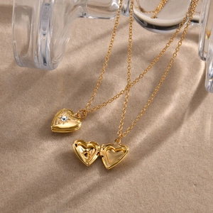Macro detail of a golden heart locket necklace with crystal, showing open and closed states