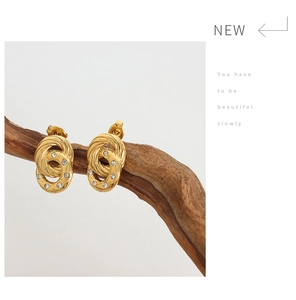Detail of 18K gold plated double hoop earrings with white zircon on a wooden branch