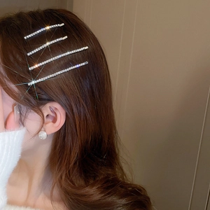 Close-up of four silver side hairpins with shiny crystals on model for hairstyle