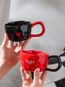 Detail of heart pattern ceramic mugs with Love lettering held in hands for couples