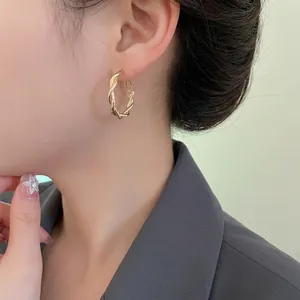 Twisted gold hoop earrings featuring minimalist geometric design on model for daily wear