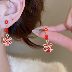 Détail macro des boucles d'oreilles lion avec émail rouge et finition dorée