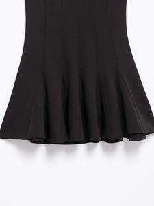 Detail shot of the pleated hemline and fabric texture of the black mini dress