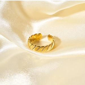 Close-up of golden twisted rope ring on champagne silk showing elegant metallic texture