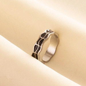 Détail d'une bague ouverte en acier 304 avec des rayures en émail noir sur tissu beige