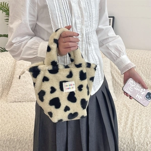 Detailed view of the plush tote bag featuring black heart patterns and brand fabric label