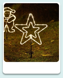 Detail of warm white solar star and Santa stake lights on outdoor night lawn