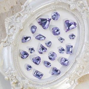 Various purple K9 crystal nail art gems in a vintage white frame on marble background