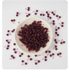 Overhead view of miniature deep purple cherry models in a bowl for DIY cake decoration