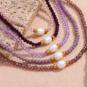 Detailed view of layered beaded necklaces featuring freshwater pearls and purple crystals