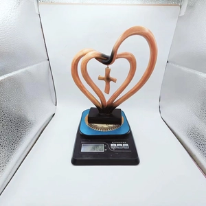 Detail of interlocking wooden heart sculpture with central cross on black base