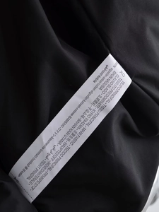 Gros plan de l'étiquette d'entretien indiquant 100% coton et taille XC sur le manteau