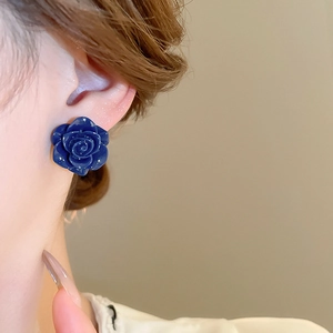 Gros plan d'une boucle d'oreille rose bleu foncé portée avec pétales 3D brillants