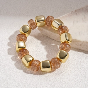Detailed macro view of gold-plated geometric beads and glitter resin beads on a stone base