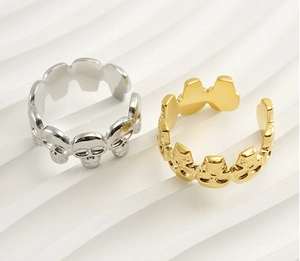 Detailed view of punk skull rings in gold and silver finish on white geometric display