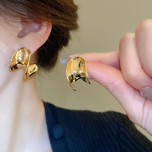Detailed view of polished gold C-shaped curved earrings with a mirror finish on model