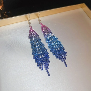 Macro shot of long gradient pink-blue tassel earrings with shimmering crystals on display