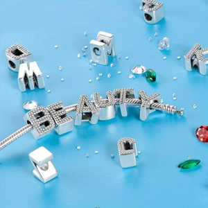 Close-up of BEAUTY letter charms with crystal inlay on a silver plated DIY bracelet
