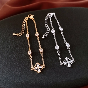 Detail of clover flower bracelets in gold and silver finish with zircon crystals