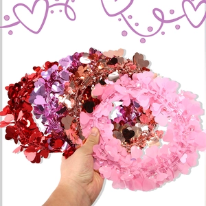 Detail of red, purple, rose gold, and pink heart sequin garlands held for party decor