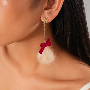 Close-up of snowflake stud earrings with red velvet bow and beige faux fur pompom ball