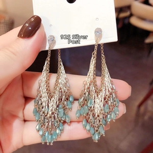 Detailed macro view of 925 silver needle tassel earrings with light blue teardrop beads