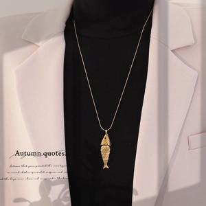 Detail of a vintage golden koi fish pendant necklace with intricate scale textures on a sweater