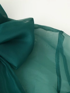 Detaillierte Nahaufnahme von dunkelgrünem Organza-Stoff mit feiner Netzstruktur und Saum