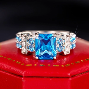 Macro shot of rectangular blue gemstone ring with pave diamonds on red jewelry box