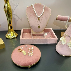Elegant jewelry display rack featuring gold necklaces, pearl earrings, and rings on pink velvet