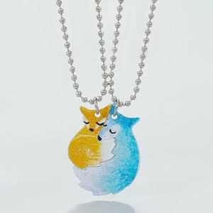 Detail of interlocking fox puzzle pendants in yellow and blue on silver bead chains