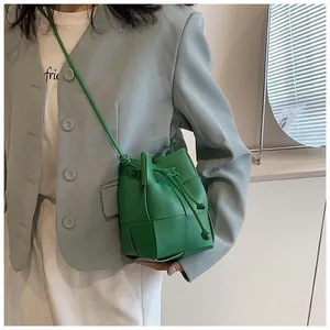 Detail of green woven leather bucket bag with drawstring shown on a blue blazer