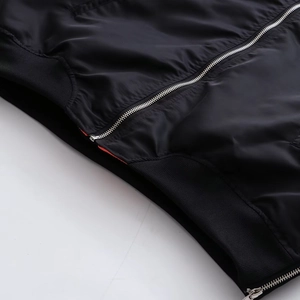Detail der schwarzen Bomberjacke mit Silberreißverschluss und orangefarbenem Futter