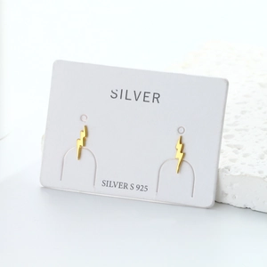 Macro detail of minimalist S925 sterling silver lightning bolt studs in golden finish