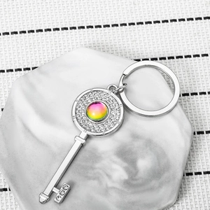 Elegant silver key keychain with sparkling crystals and rainbow gemstone on marble