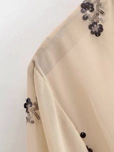 Gros plan détaillé du tissu en mousseline abricot avec sequins floraux et coutures