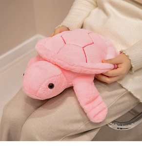 Detail of soft pink turtle plush pillow with red shell embroidery on a model lap