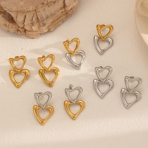 Minimalist double heart earrings in gold and silver finish on white textured surface