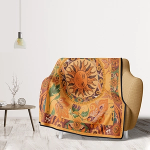 Bohemian orange throw blanket with sun totem and floral patterns draped on a sofa