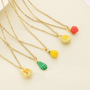 Flat lay of five gold titanium necklaces featuring colorful enamel fruit charms