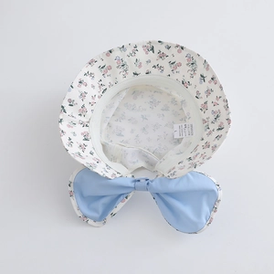Dettaglio del cappello floreale con etichetta in nylon UPF 50+ e fiocco blu