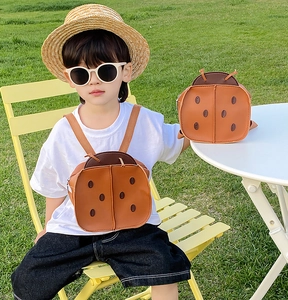 Brown beetle shaped backpack for children in PU leather shown with toddler model outdoors
