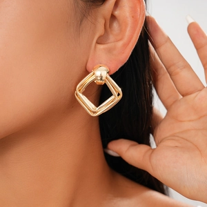 Close-up of golden geometric double-square earrings on a model showing modern chic style