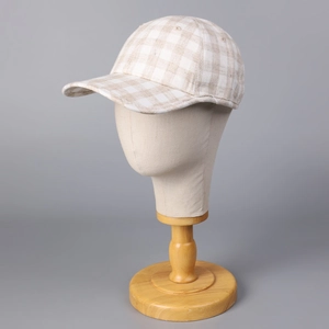 Detail view of linen plaid baseball cap on a mannequin head with natural wood base