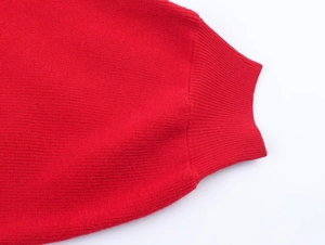 Dettaglio ravvicinato dei polsini a coste su un maglione lavorato a maglia rosso con trama fine